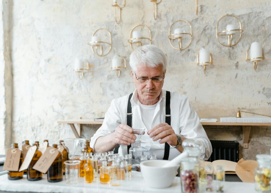 Man in White Dress Shirt Sitting at Table Making Perfume