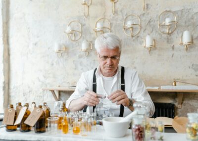 Man in White Dress Shirt Sitting at Table Making Perfume